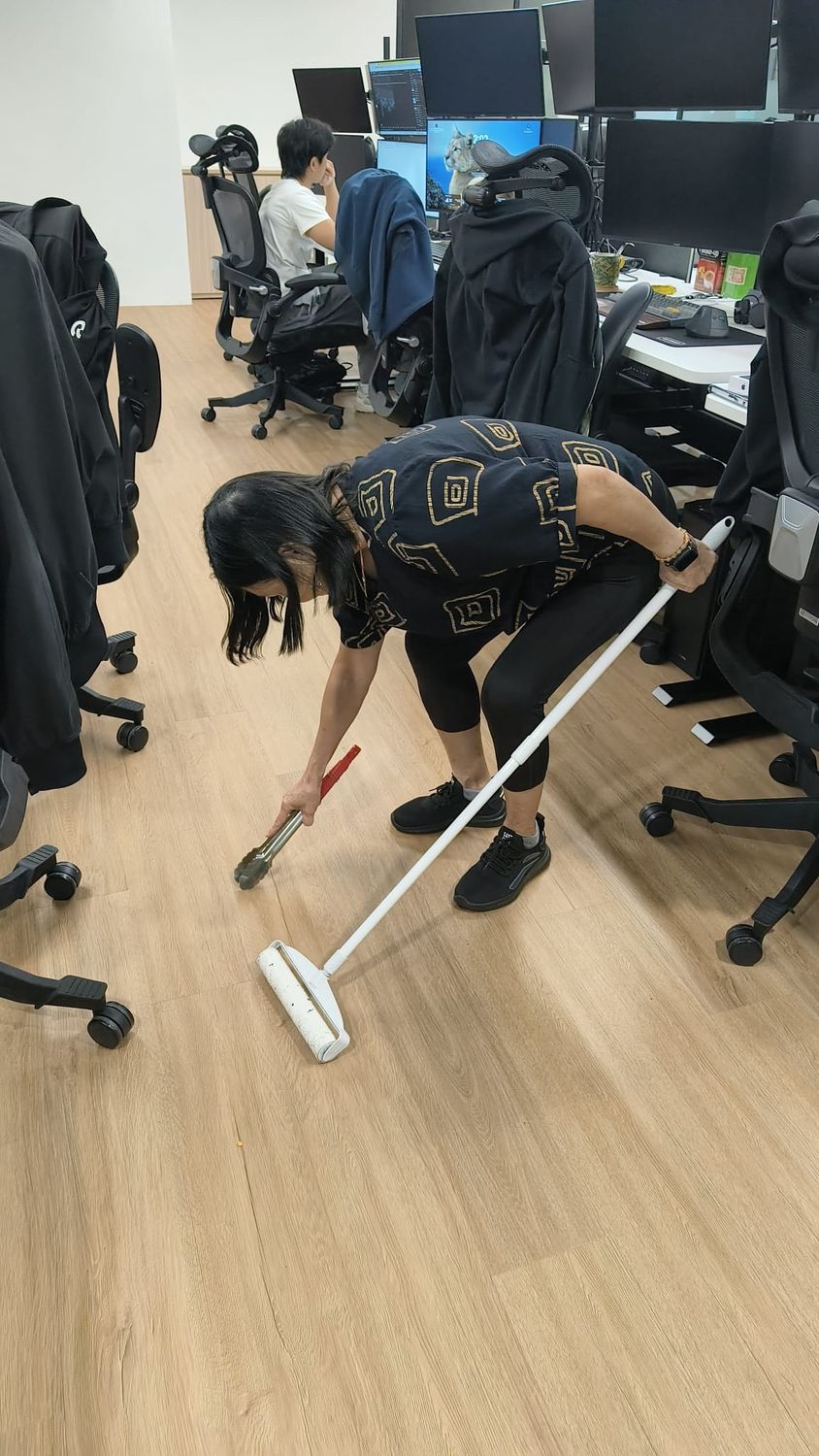 Yuki & White cleaner sweeping between workstations in an occupied Singapore office