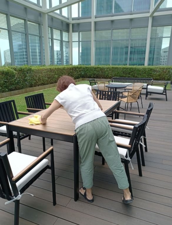 Cleaner wiping down outdoor furniture on a rooftop garden terrace