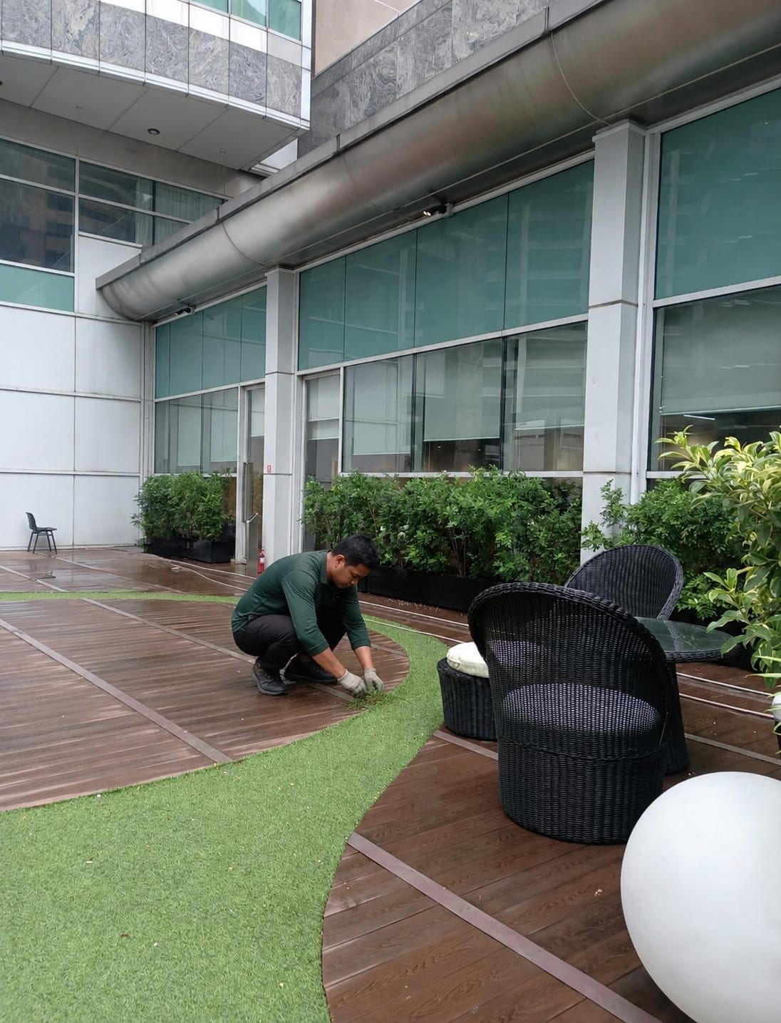 Landscape team member trimming turf edging on an office terrace