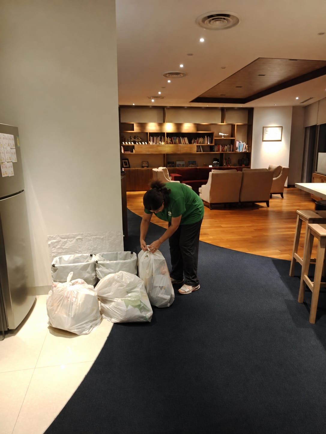 Cleaner clearing waste from an executive lounge in the evening